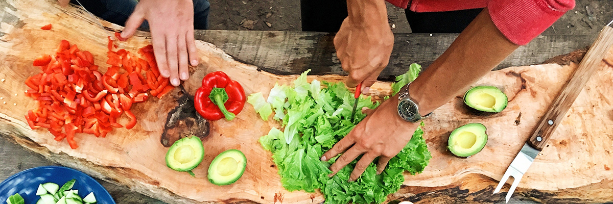 two pairs of hands chopping vegetables